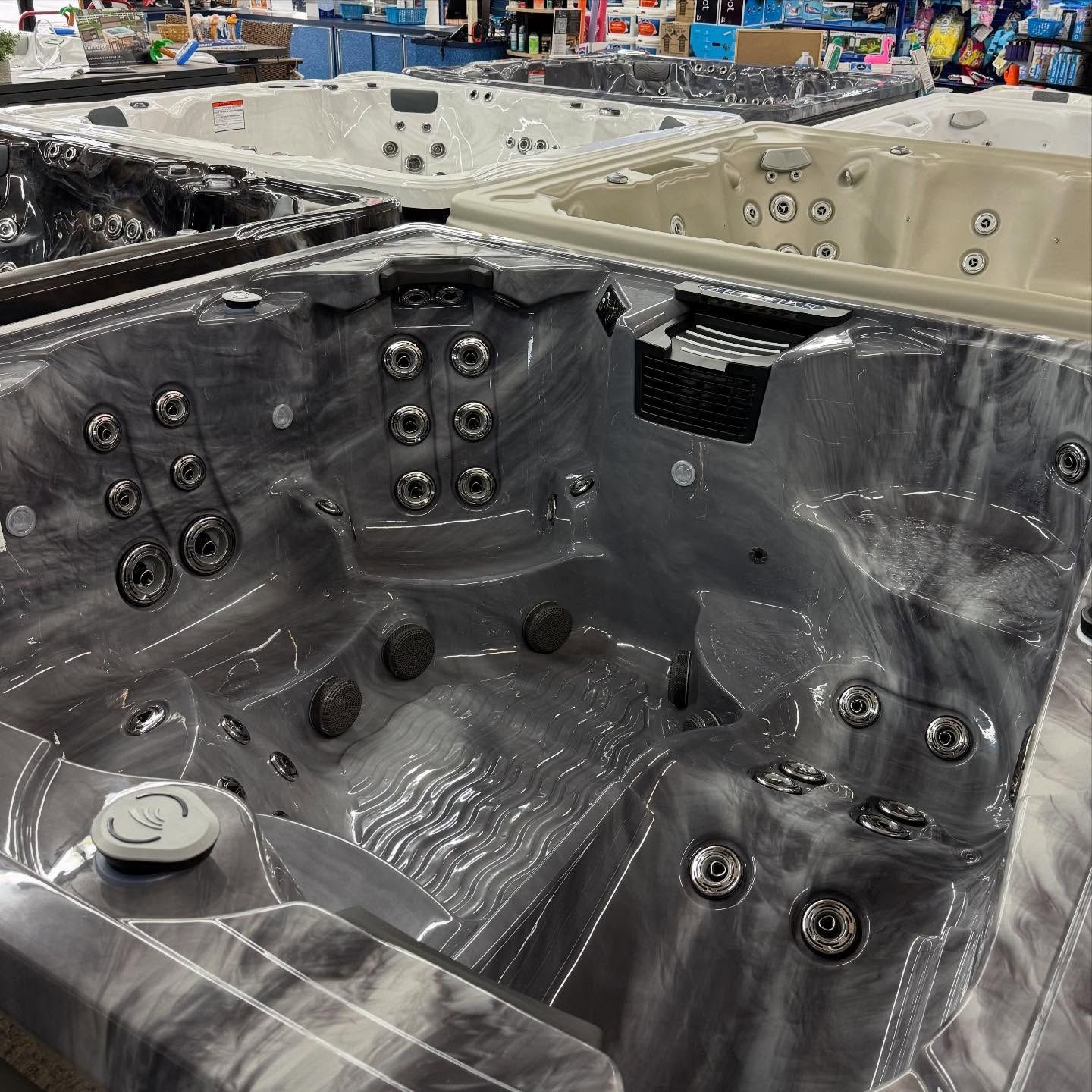 Large black spa tub showroom display with multiple jets and molded seats
