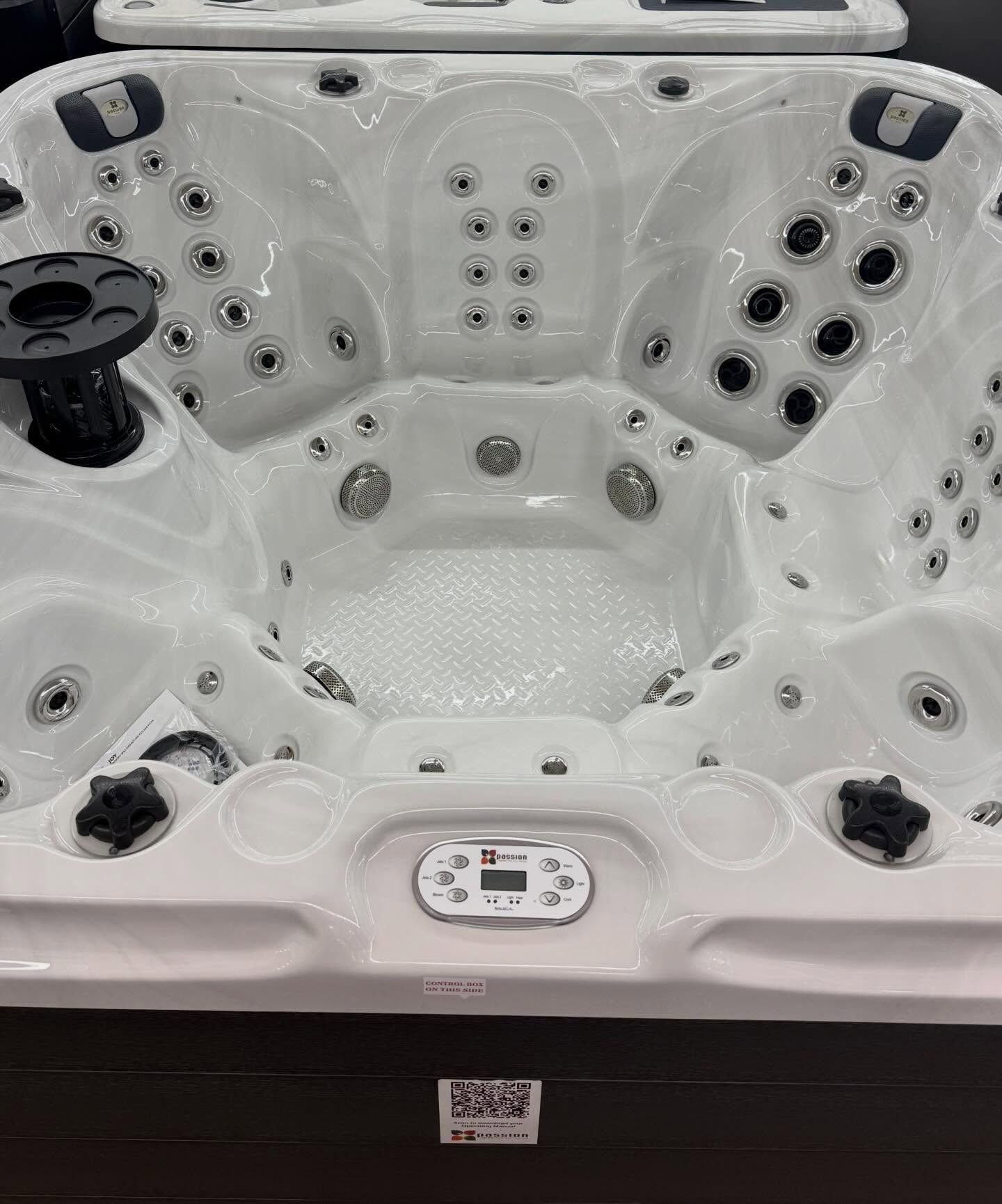 White hot tub with multiple jets and black cup holders inside a showroom display.
