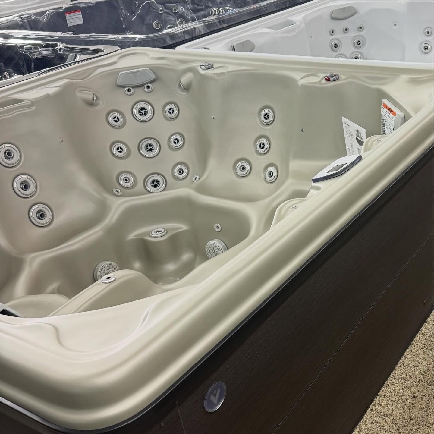 Beige outdoor hot tub with multiple jets and built-in seats beside snow-covered ground