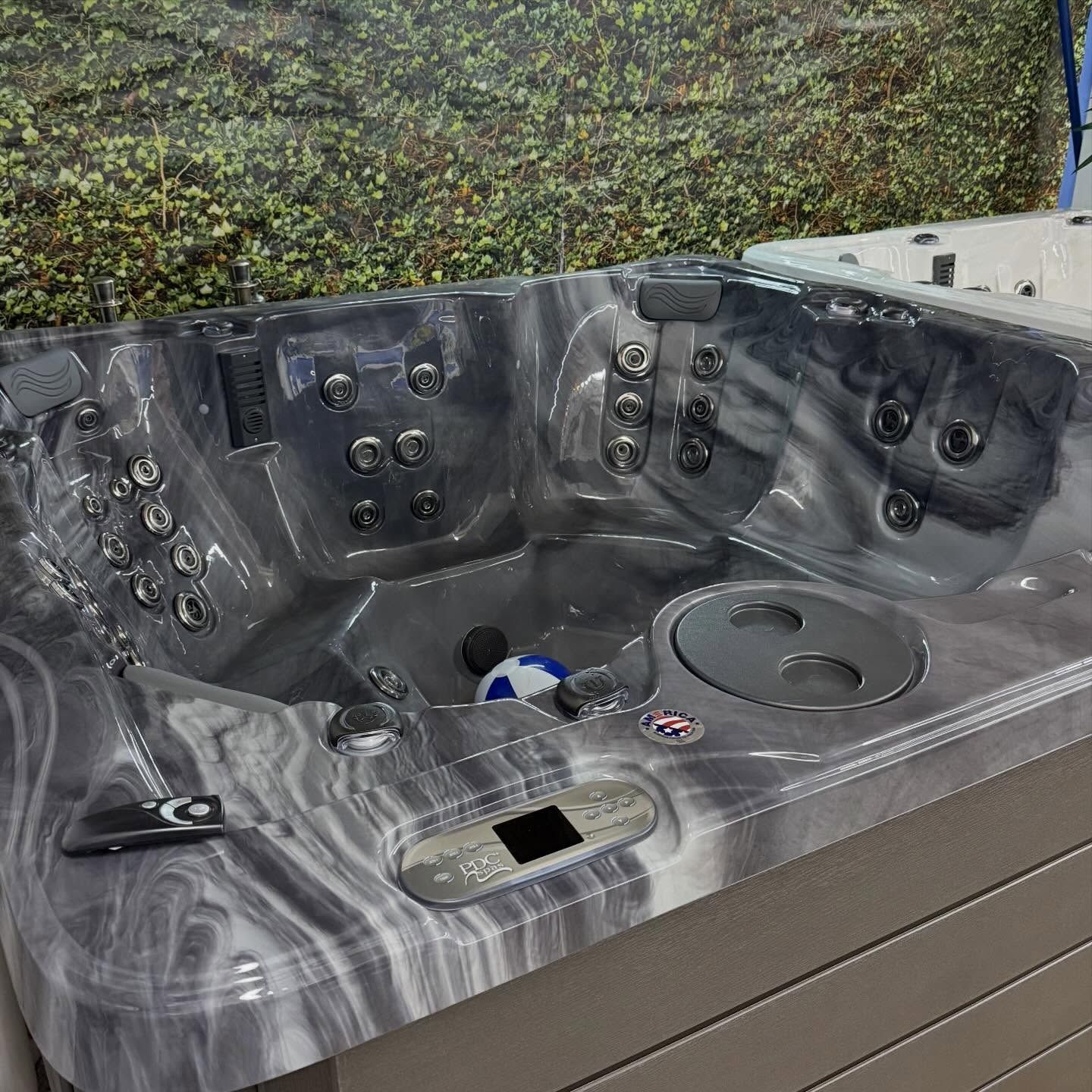 Gray marbled hot tub with multiple jets and cup holders outdoors on a deck