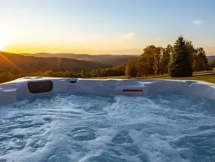 Hot tub with bubbling water overlooking a sunset mountain landscape