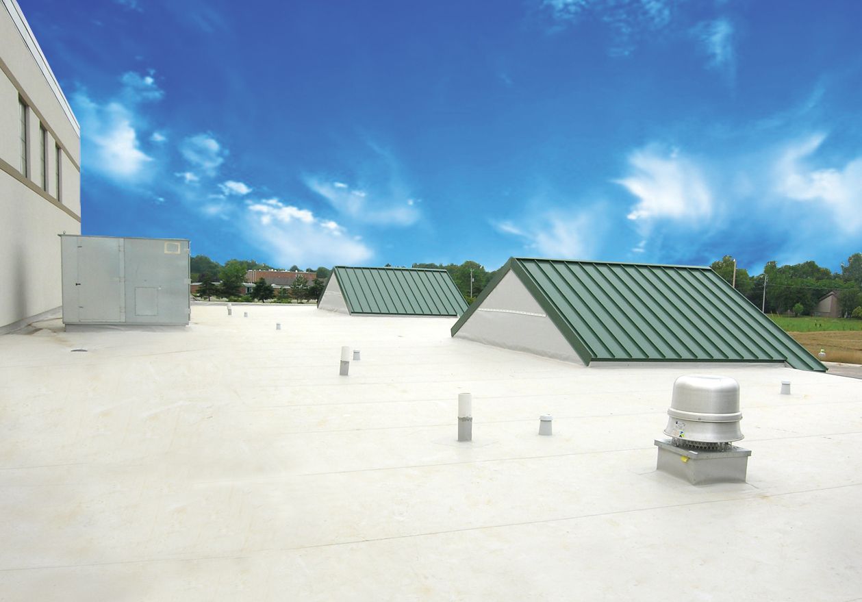 White flat roof with green metal roof sections against a blue sky.