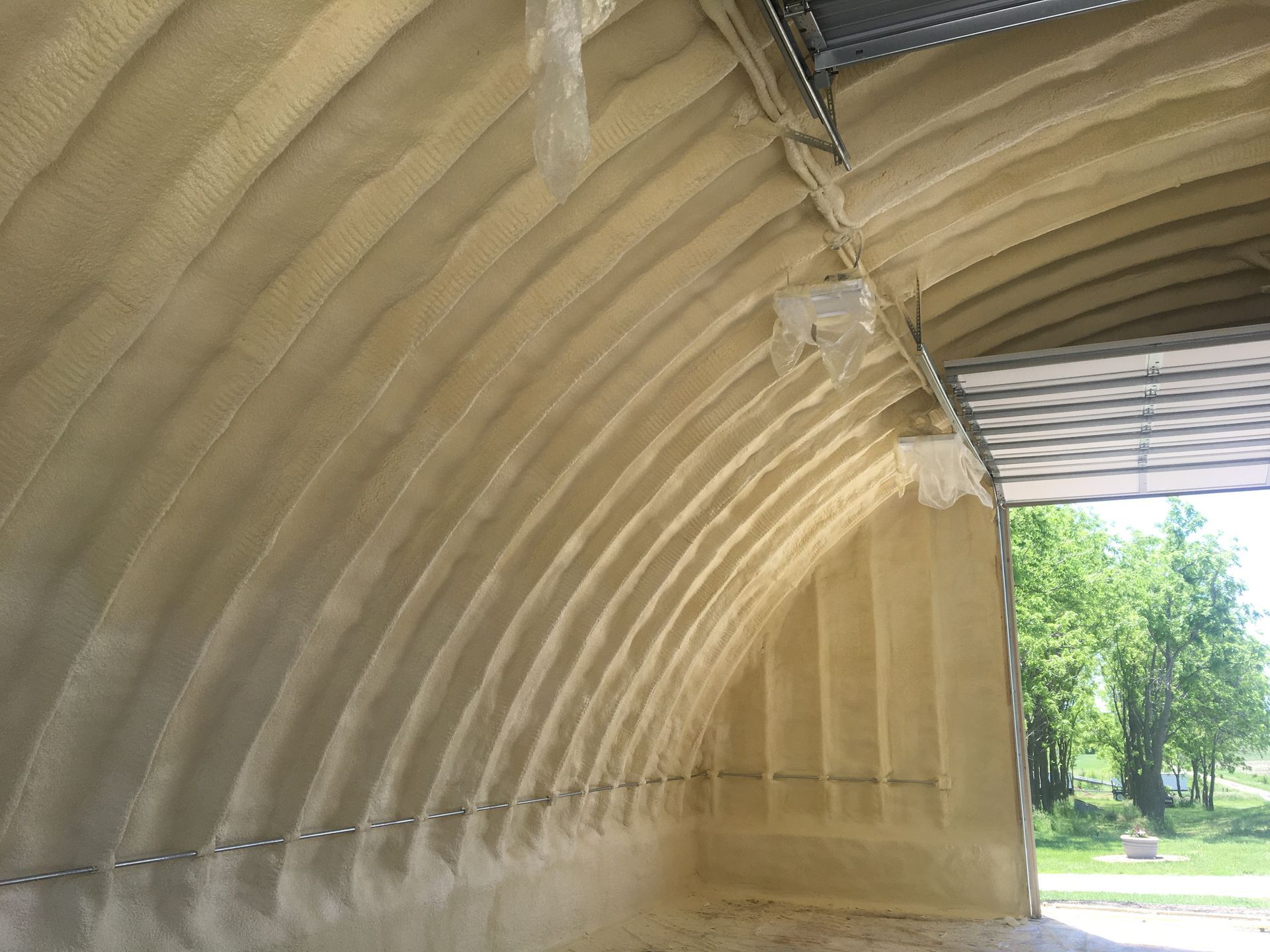 Interior view of an arched metal building with spray foam insulation on the walls and ceiling.