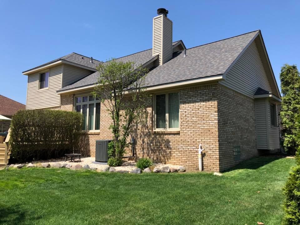 A two-story brick house with a green lawn and blue sky.