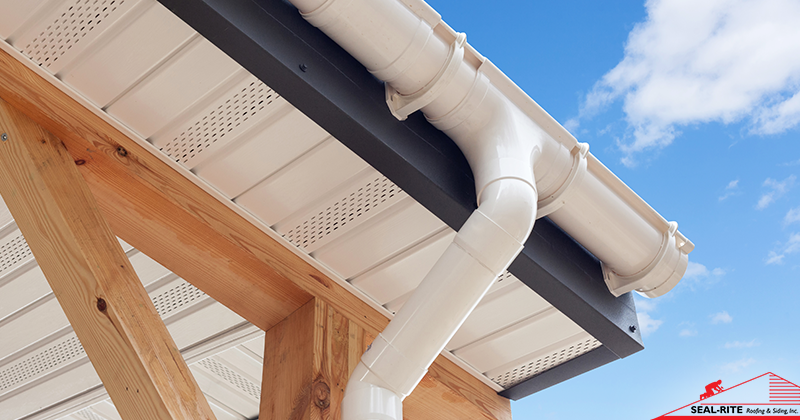 White rain gutter system on a building with a blue sky background.