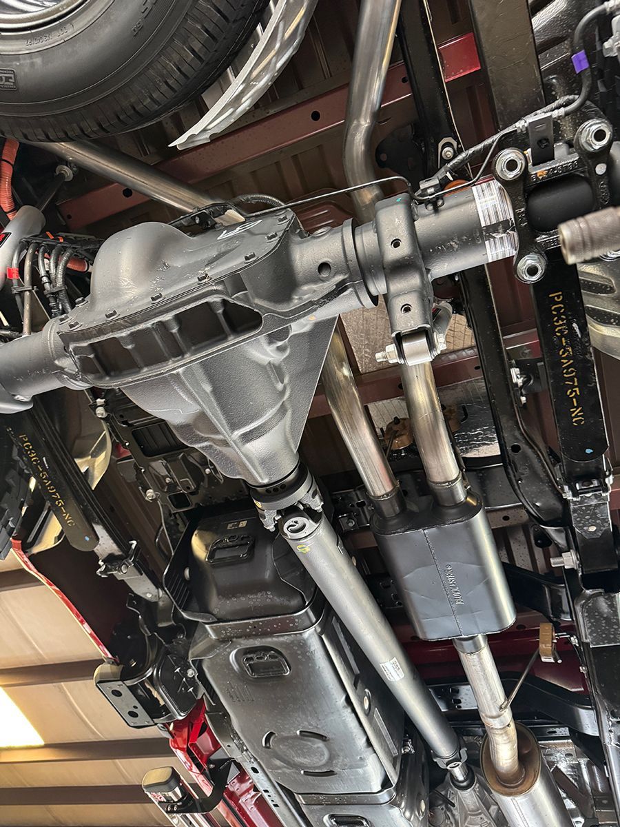 Undercarriage of a vehicle showing exhaust, driveshaft, and metal suspension components