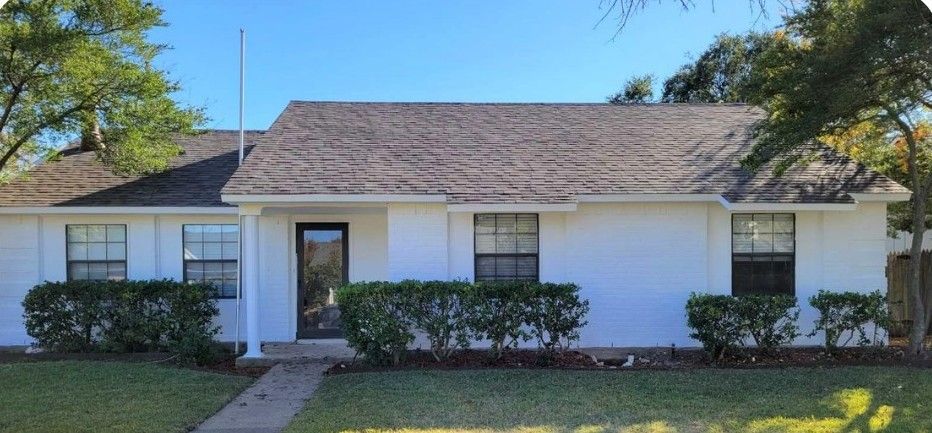 A white house with a roof and a lot of windows is for sale.