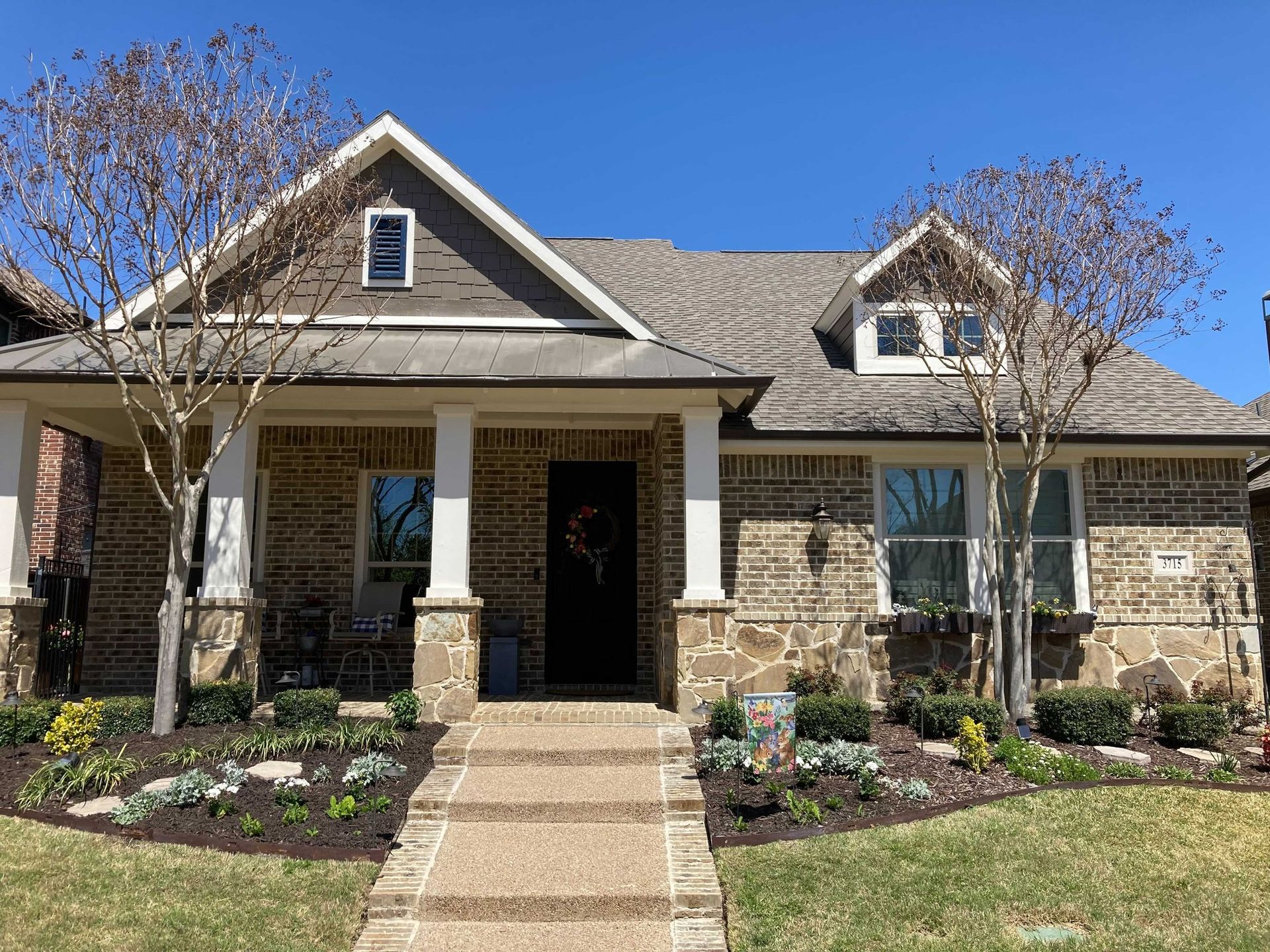A large brick house with a porch and a walkway leading to it.