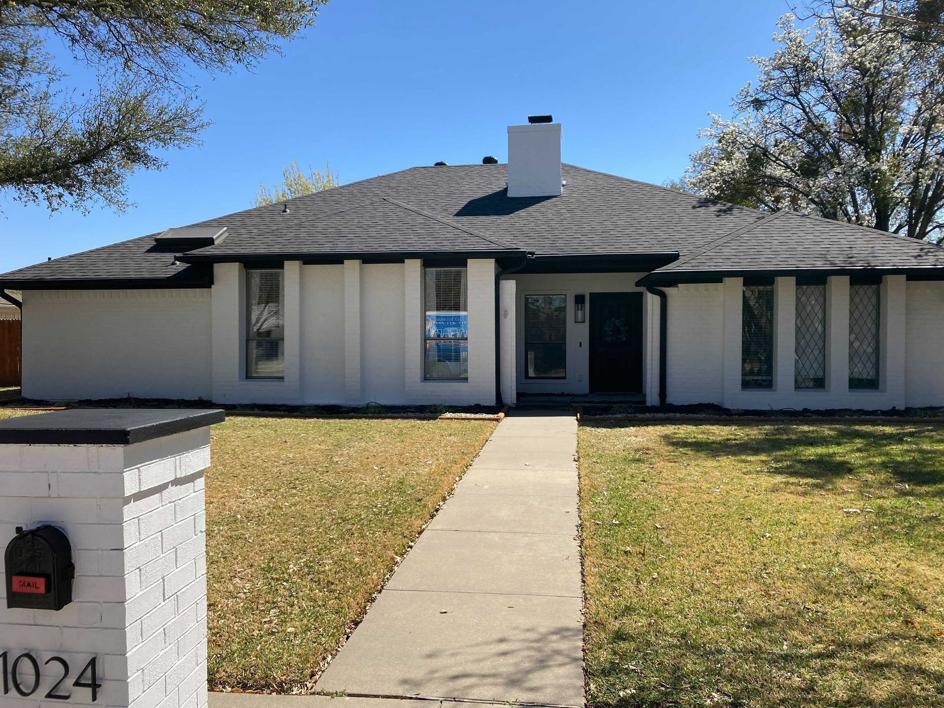 A white house with a brick mailbox in front of it.