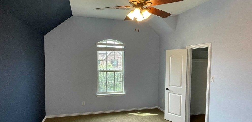 An empty bedroom with a ceiling fan and a window.