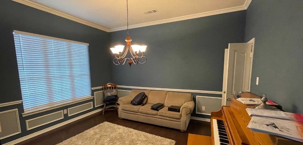 A living room with a couch , piano , and chandelier.