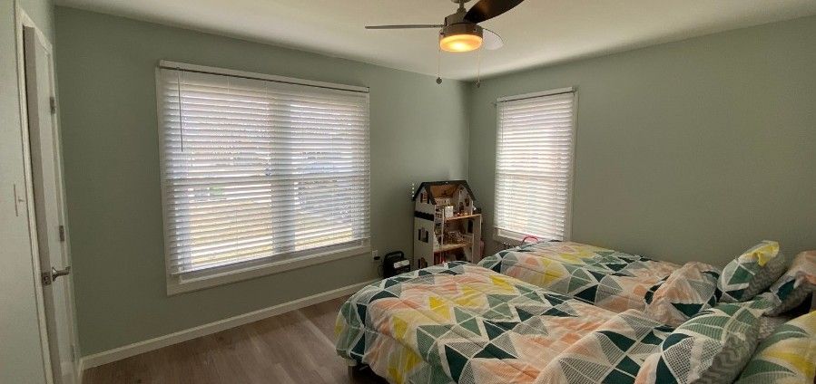 A bedroom with two beds and a ceiling fan.