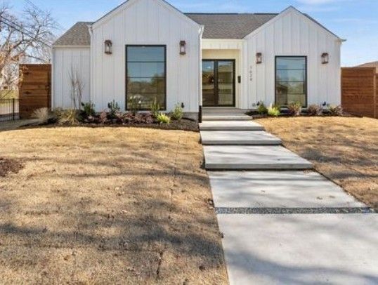A white house with a concrete walkway leading to it.