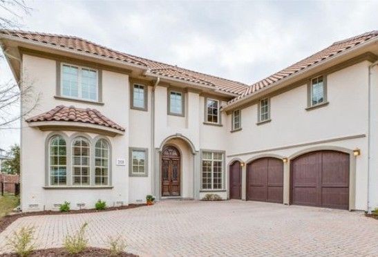 A large white house with brown garage doors and a brick driveway