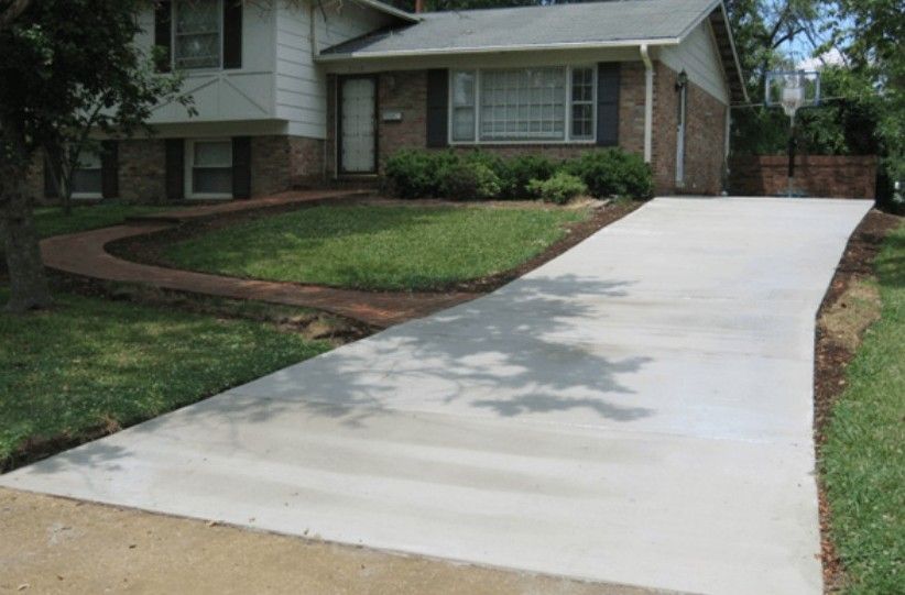 A brick house with a concrete driveway leading to it