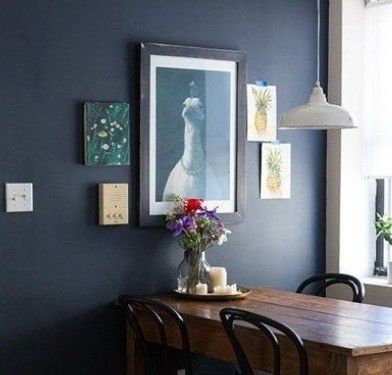 A dining room with dark blue walls and a wooden table and chairs.