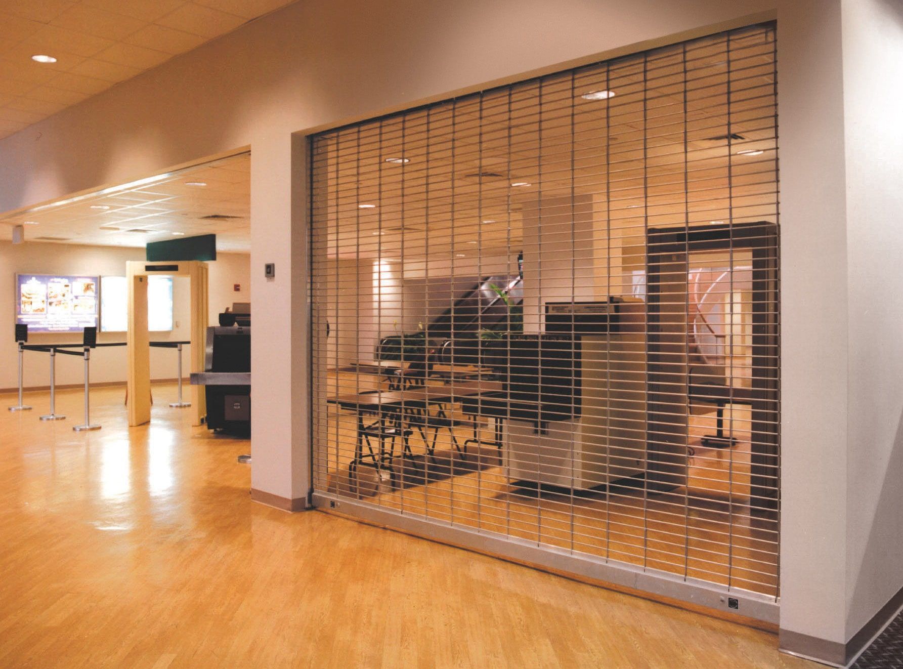 A room with tables and chairs behind a metal grille.