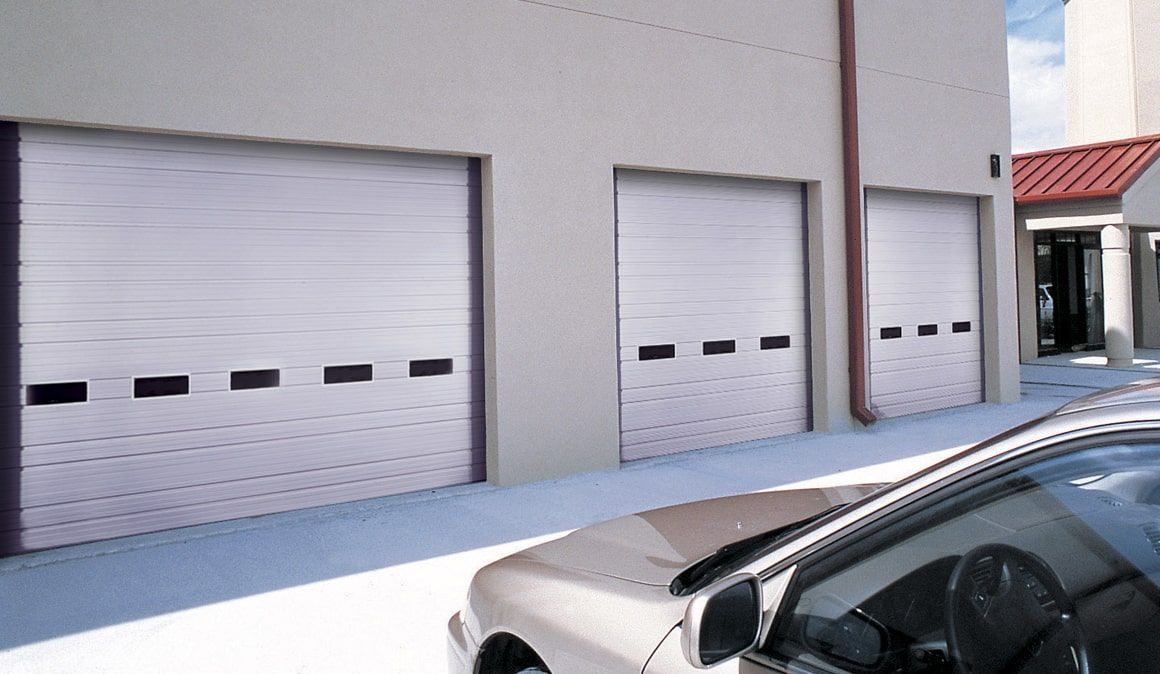 A car is parked in front of a row of garage doors