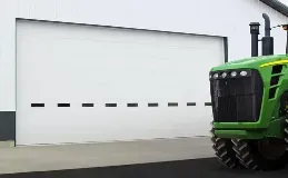 A green tractor is parked in front of a white garage door.