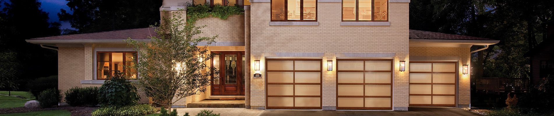 A large house with a lot of windows and a garage is lit up at night.