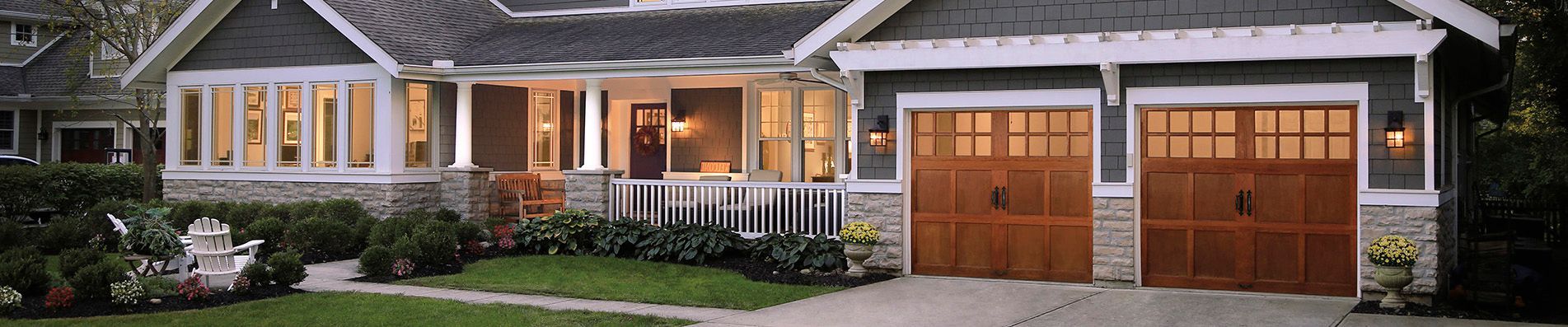 A house with two wooden garage doors in front of it