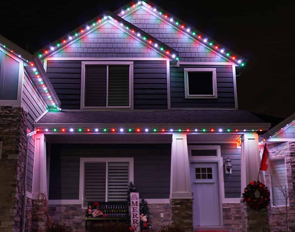 A house with christmas lights on it is lit up at night.