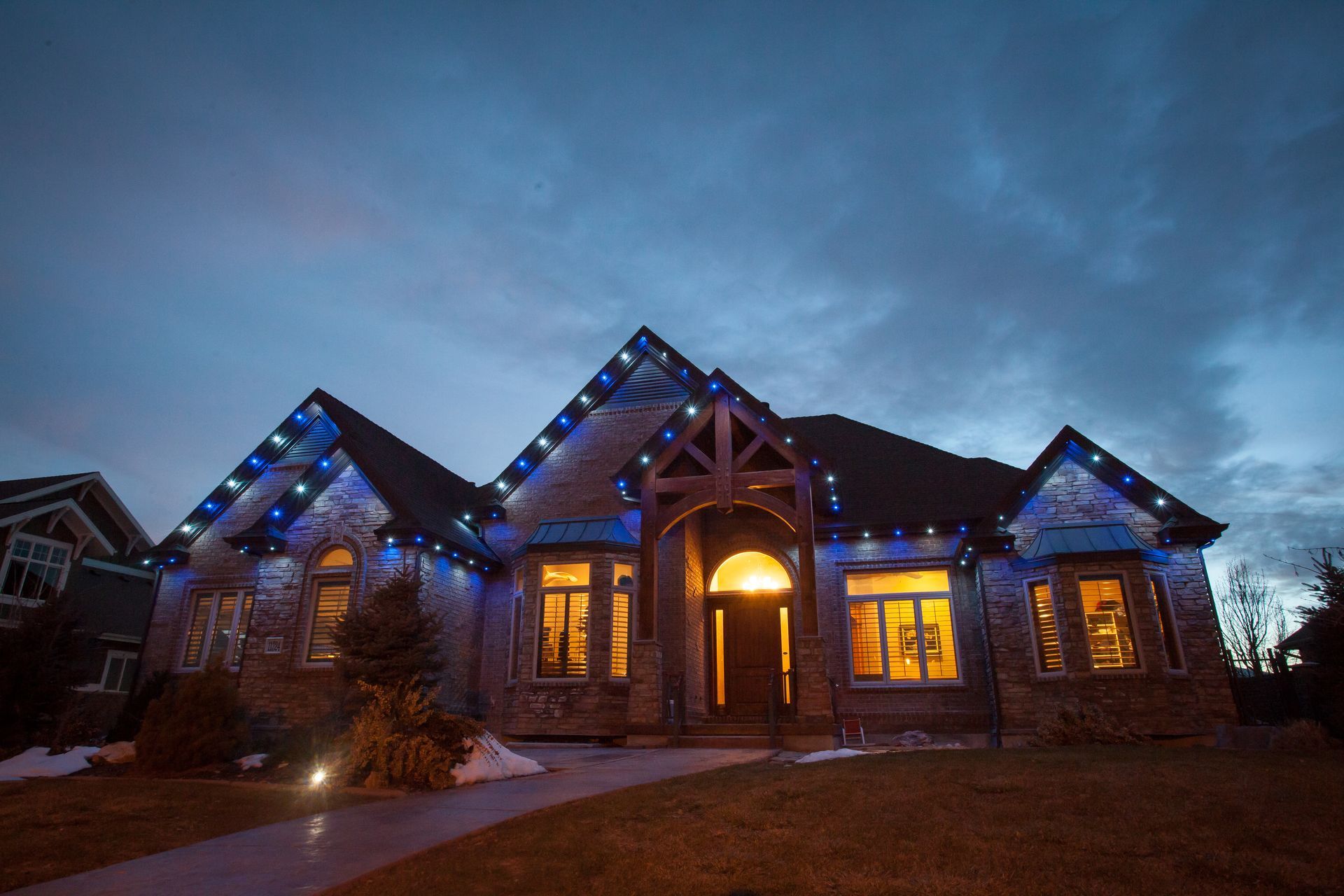 A large house is lit up with blue christmas lights at night.