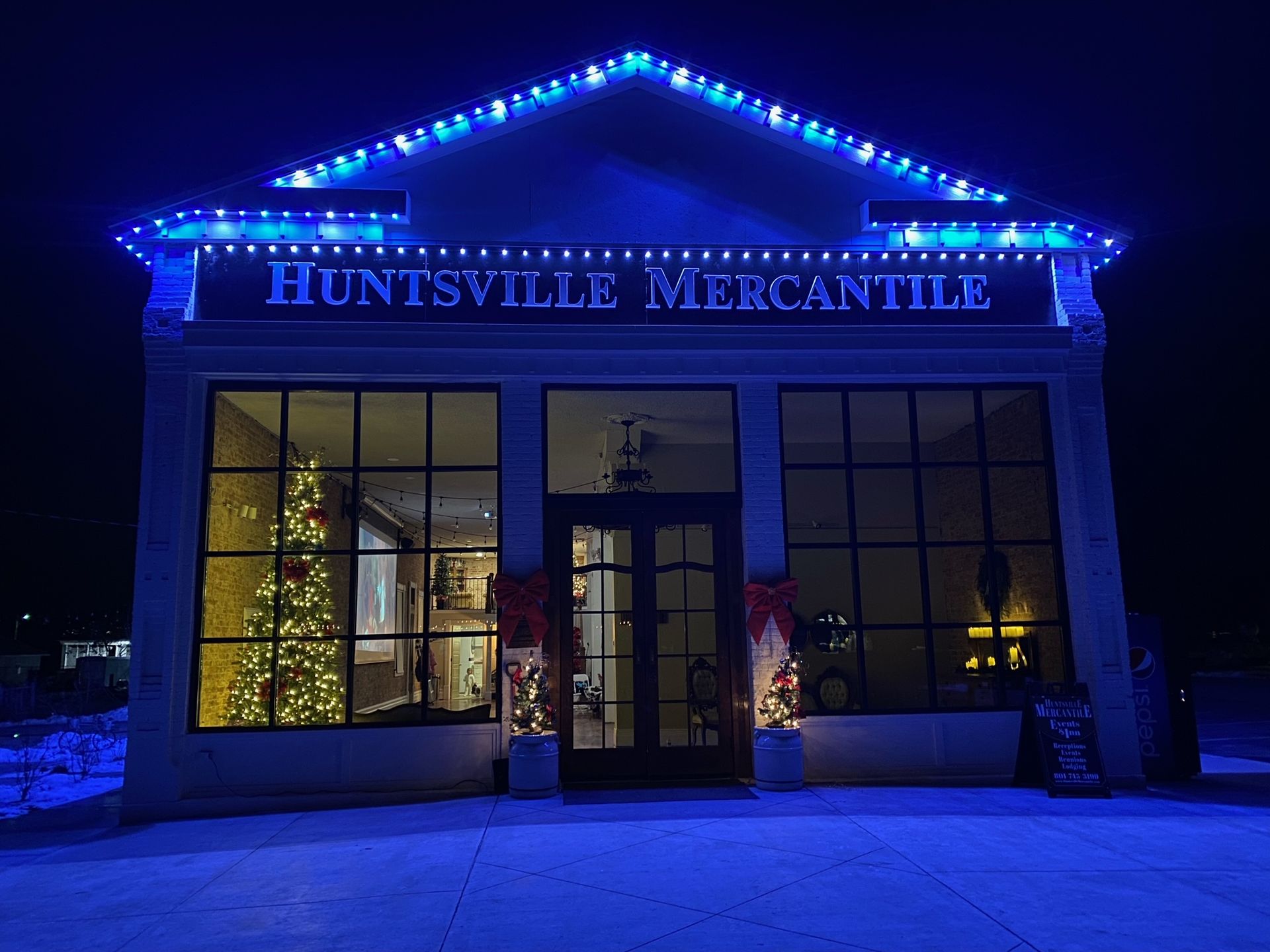 A building with christmas lights on it is lit up at night.