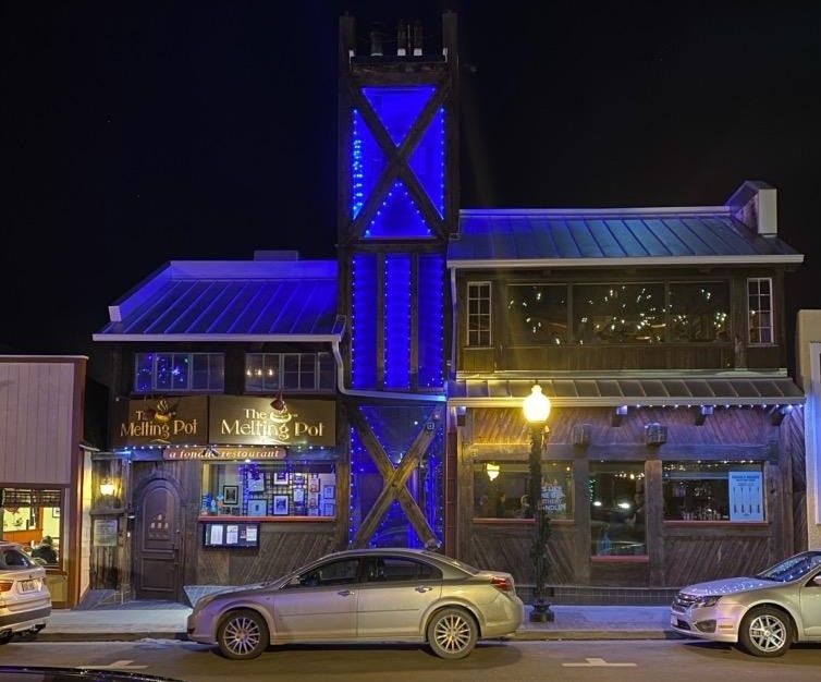 A car is parked in front of a building with a blue light on it
