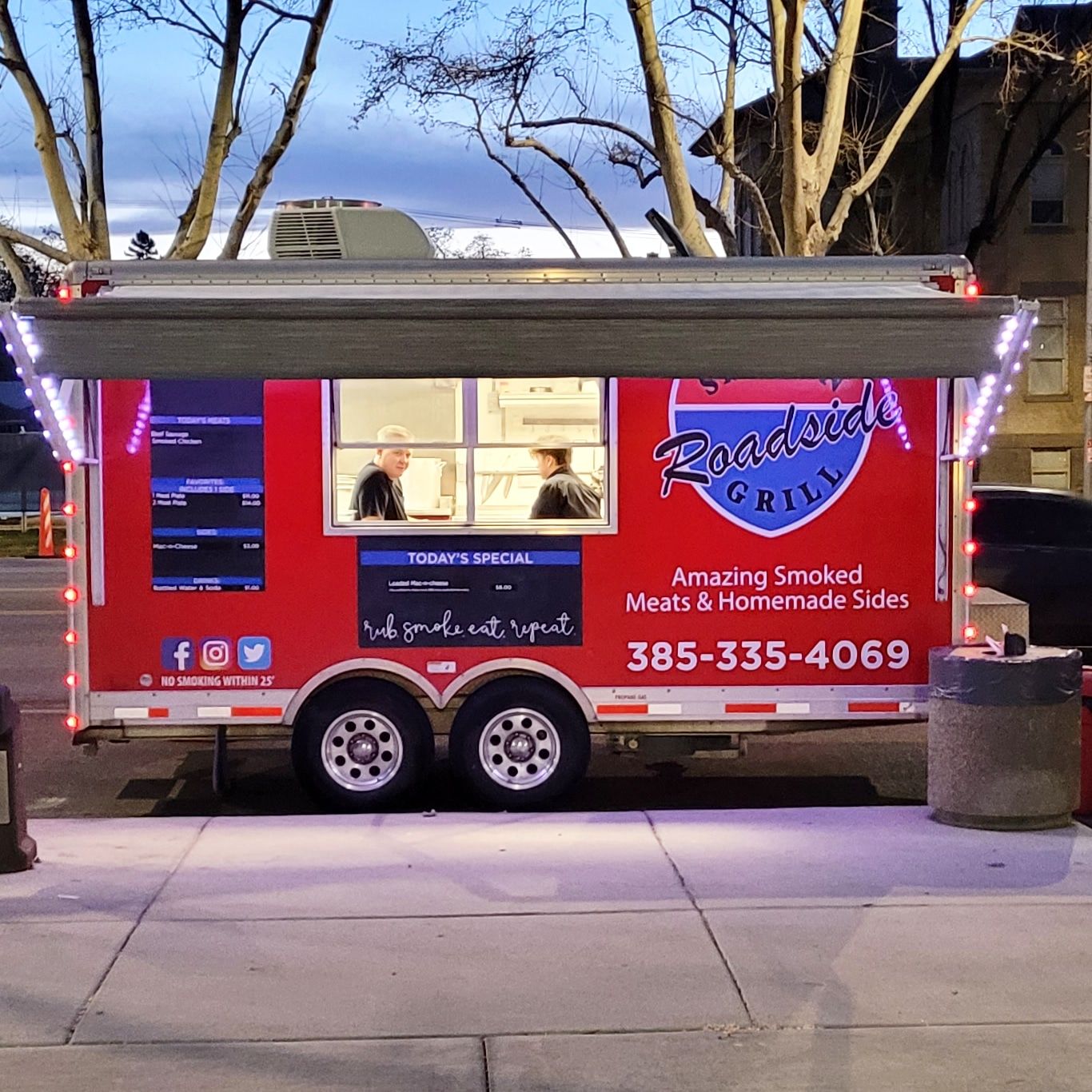 A red food truck is parked on the side of the road