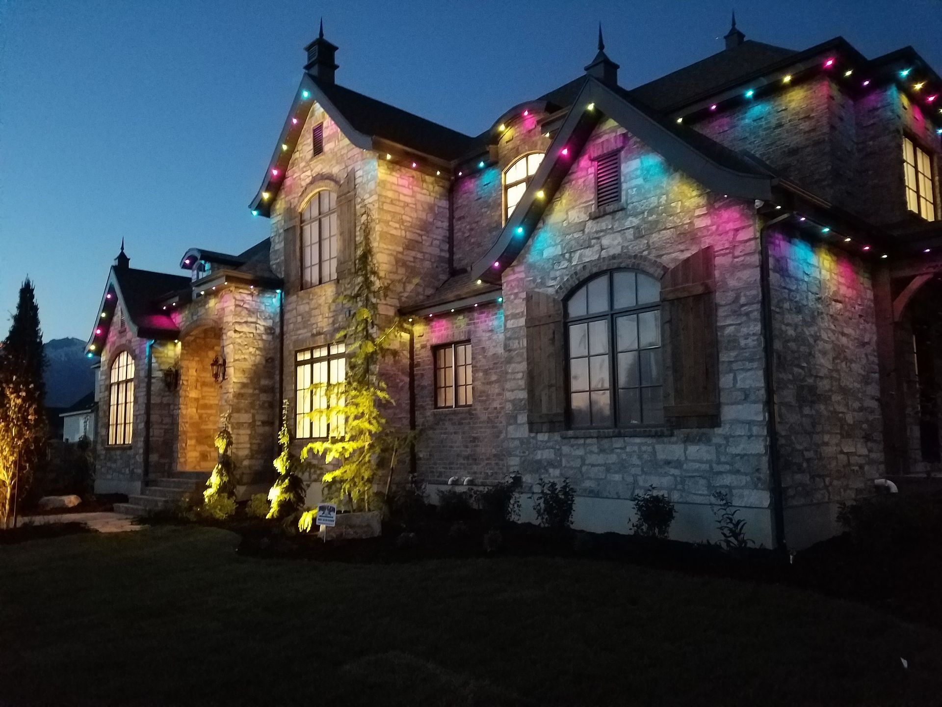A large house is decorated with christmas lights at night