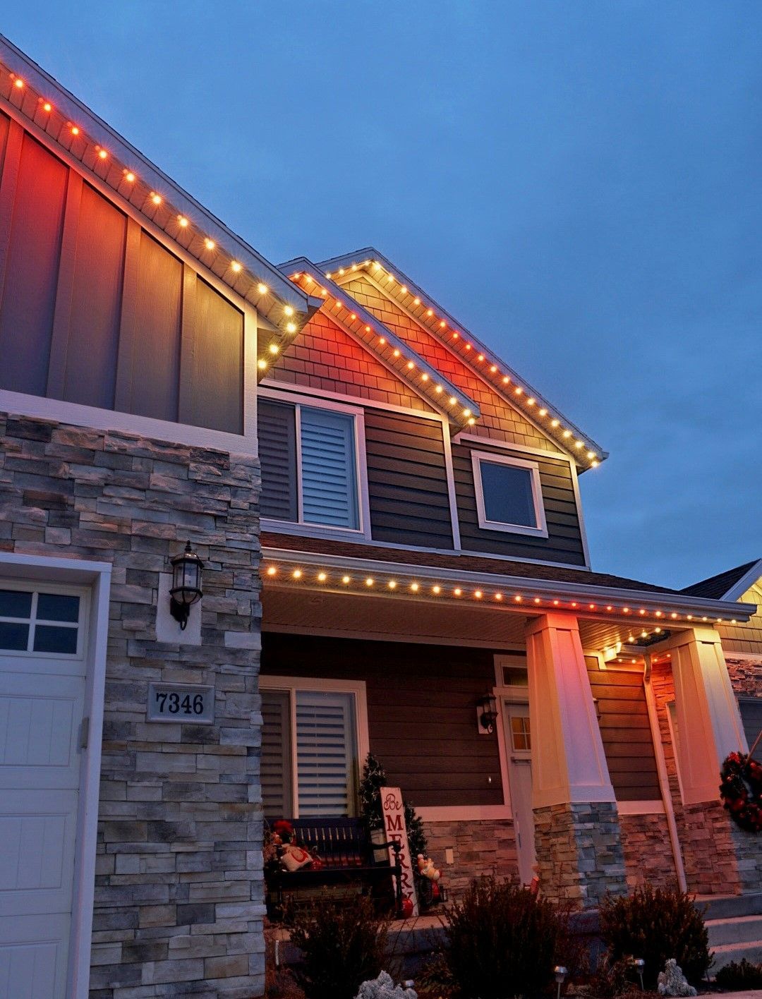A house with christmas lights on the roof is lit up at night.