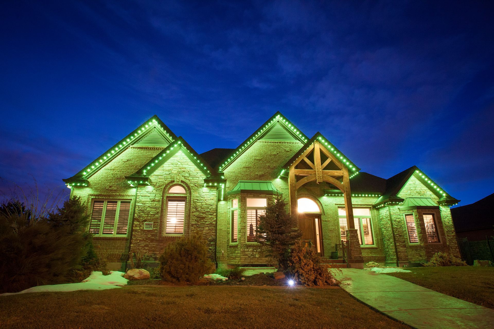 A large house is lit up with green lights at night.