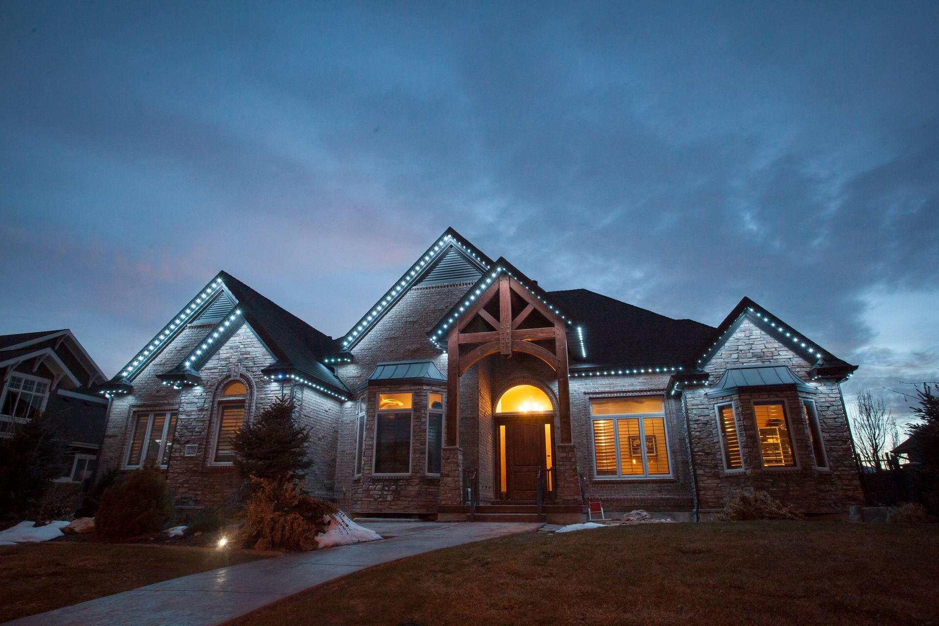 A large house with christmas lights on it is lit up at night.