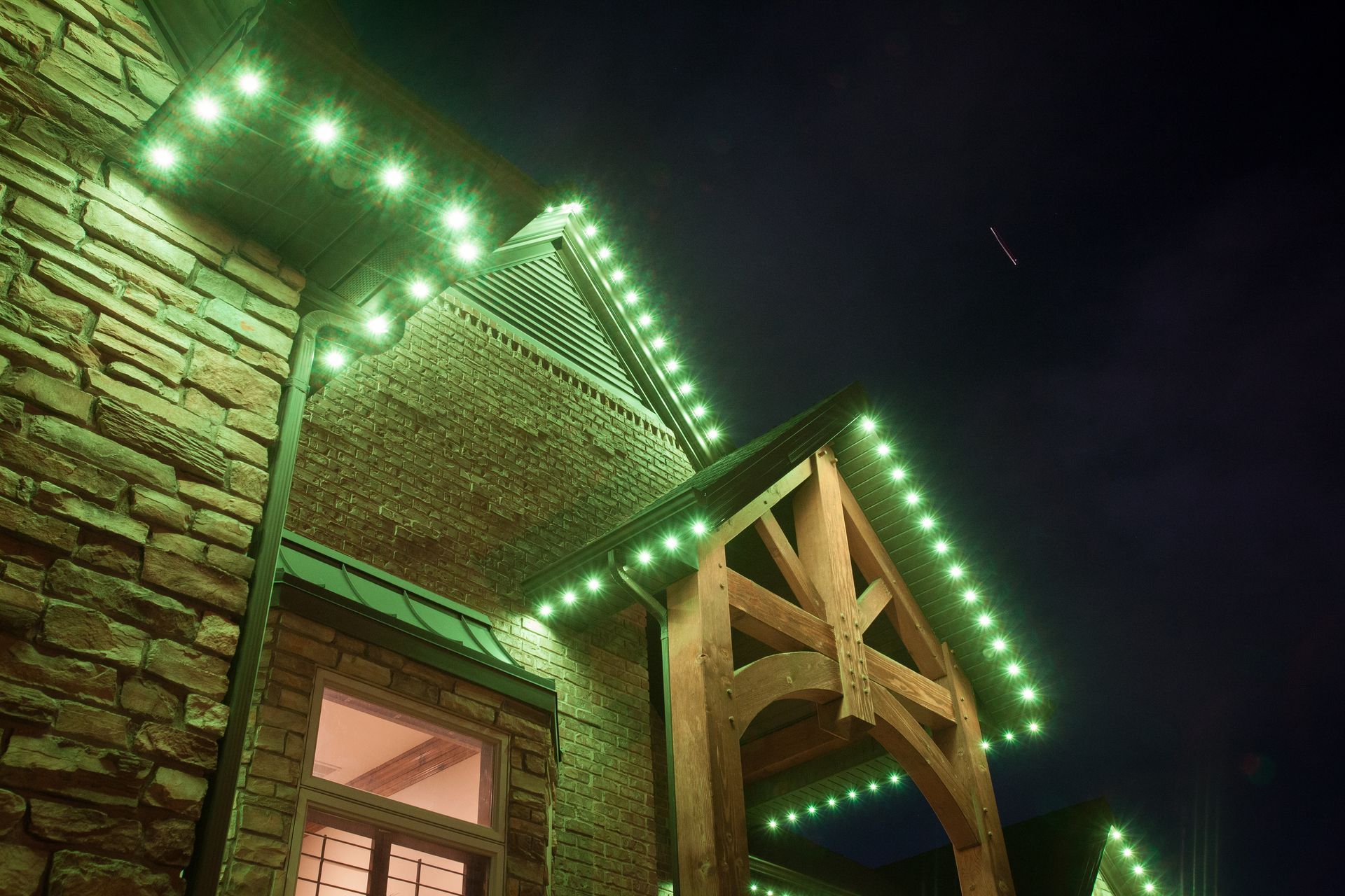 A brick building with green lights on the roof at night.