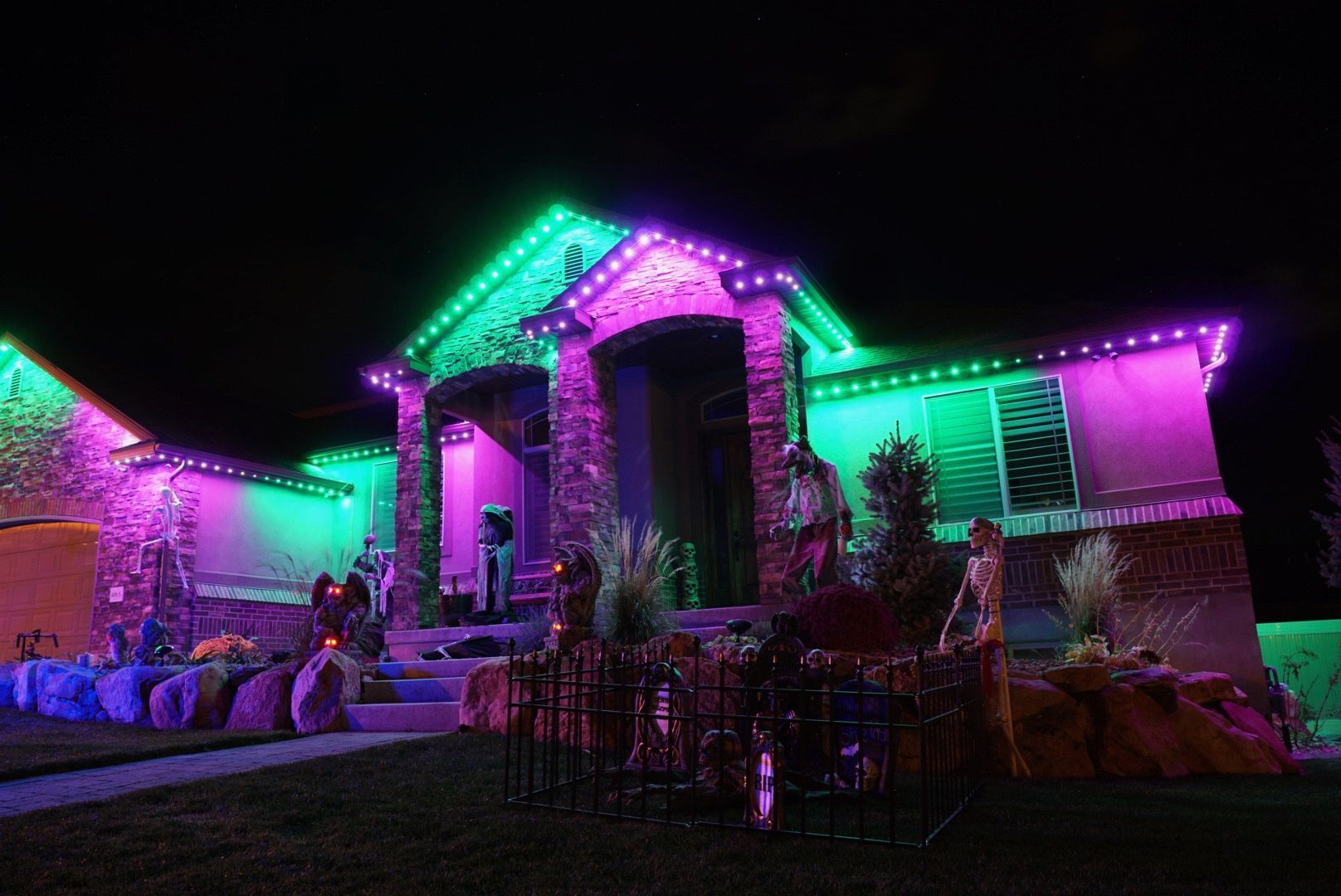 A house is decorated for halloween with purple and green lights.