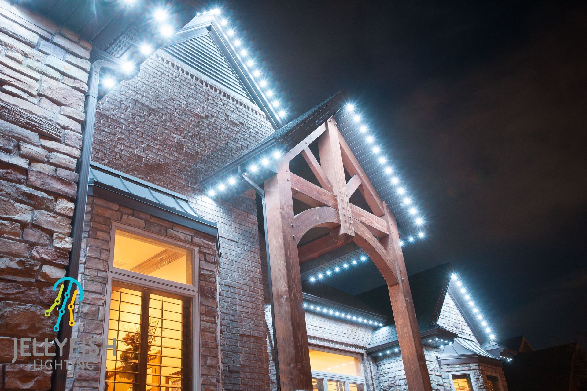 The front of a house is lit up at night with white lights.