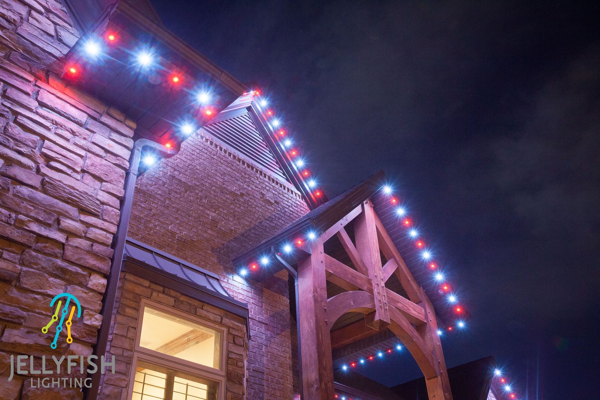 A house with christmas lights on the roof is lit up at night.