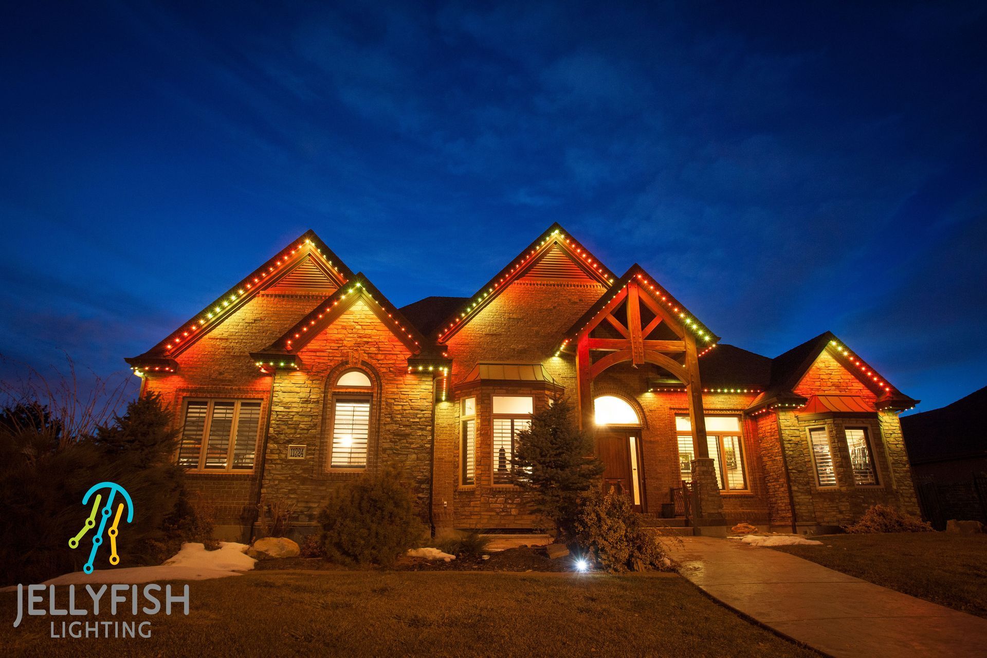 A large house with christmas lights on it is lit up at night.