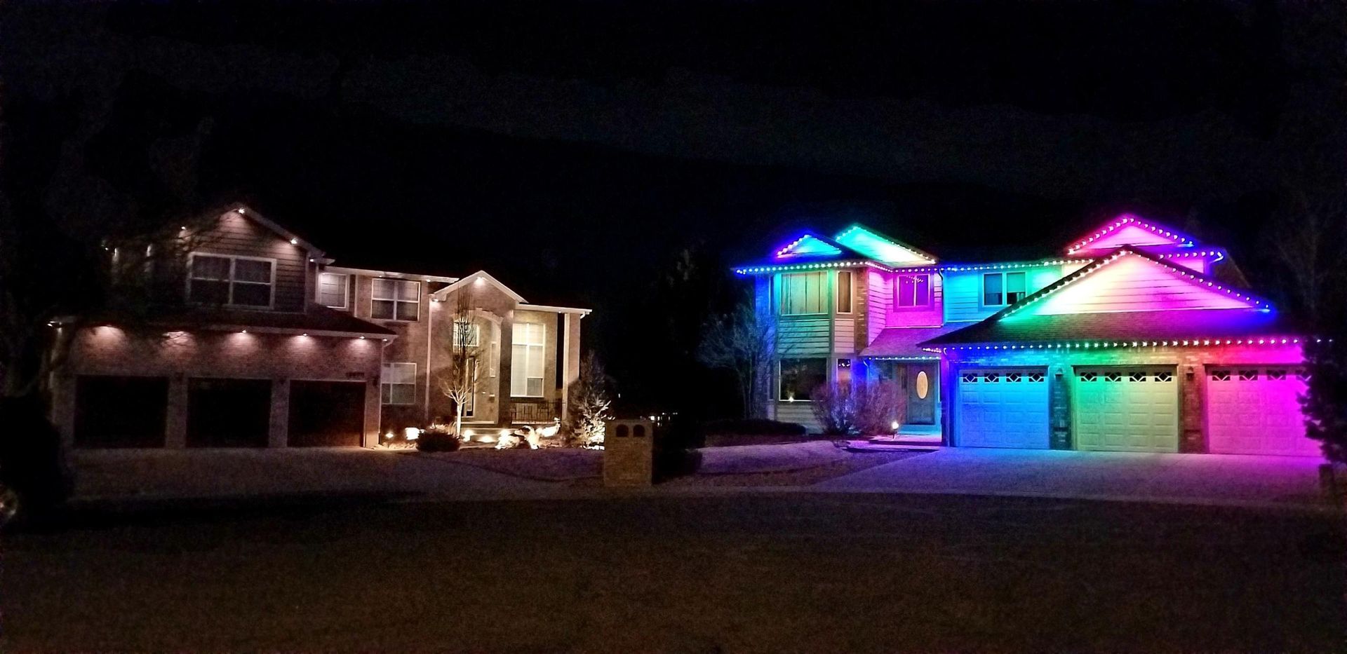 Two houses are lit up with rainbow lights at night.