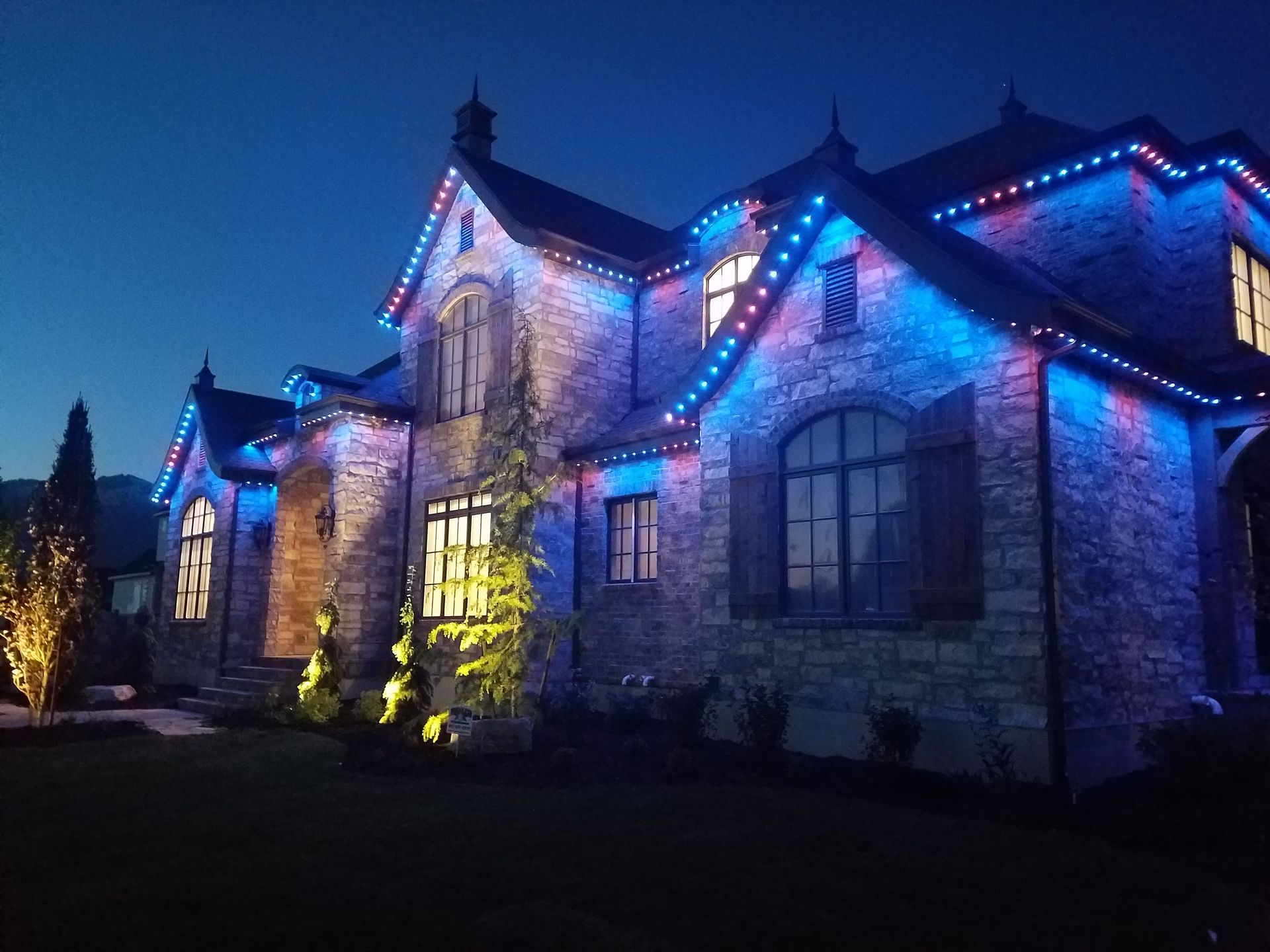 A large house is lit up with blue lights at night.