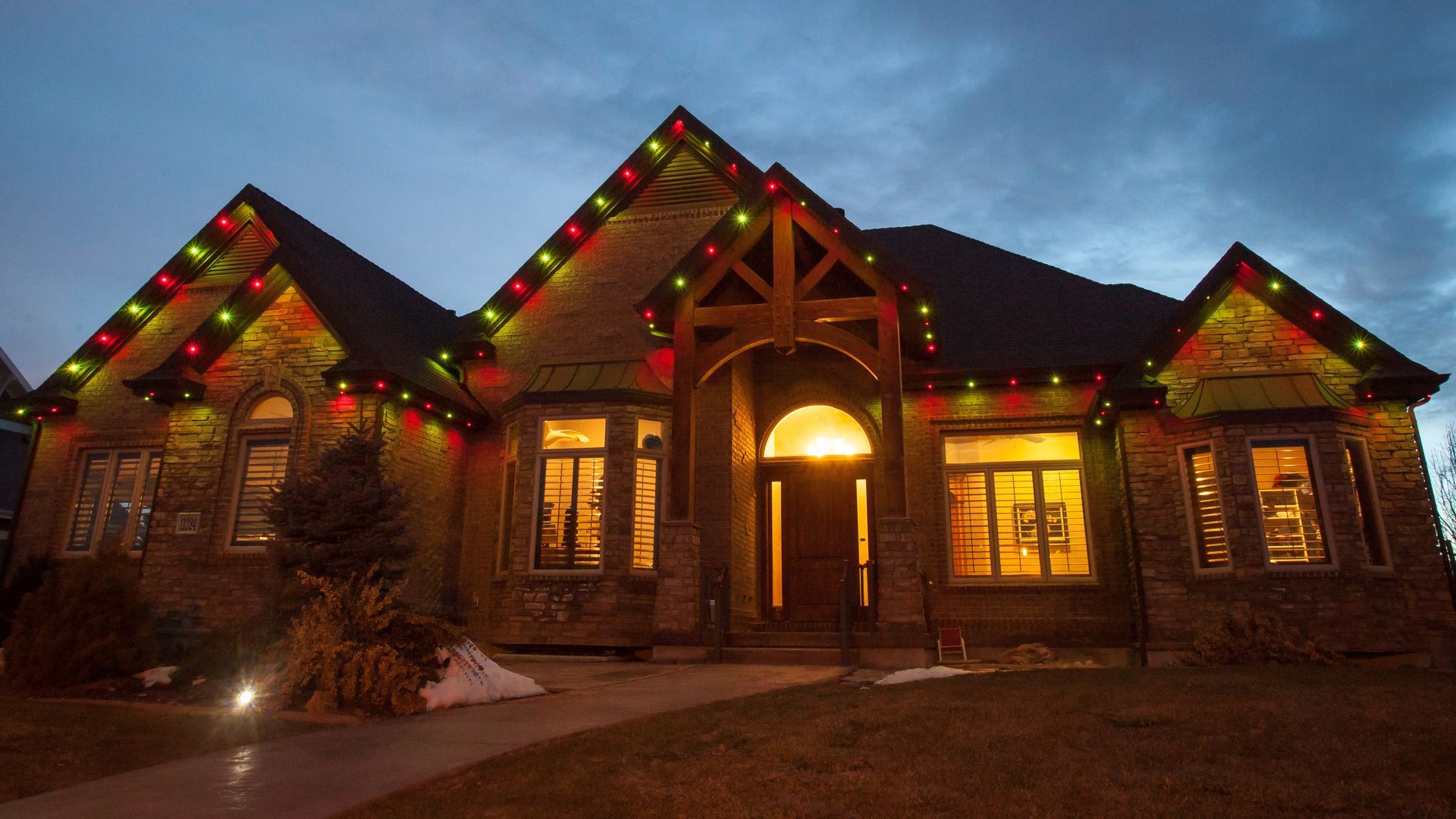 A large house is decorated with christmas lights at night.