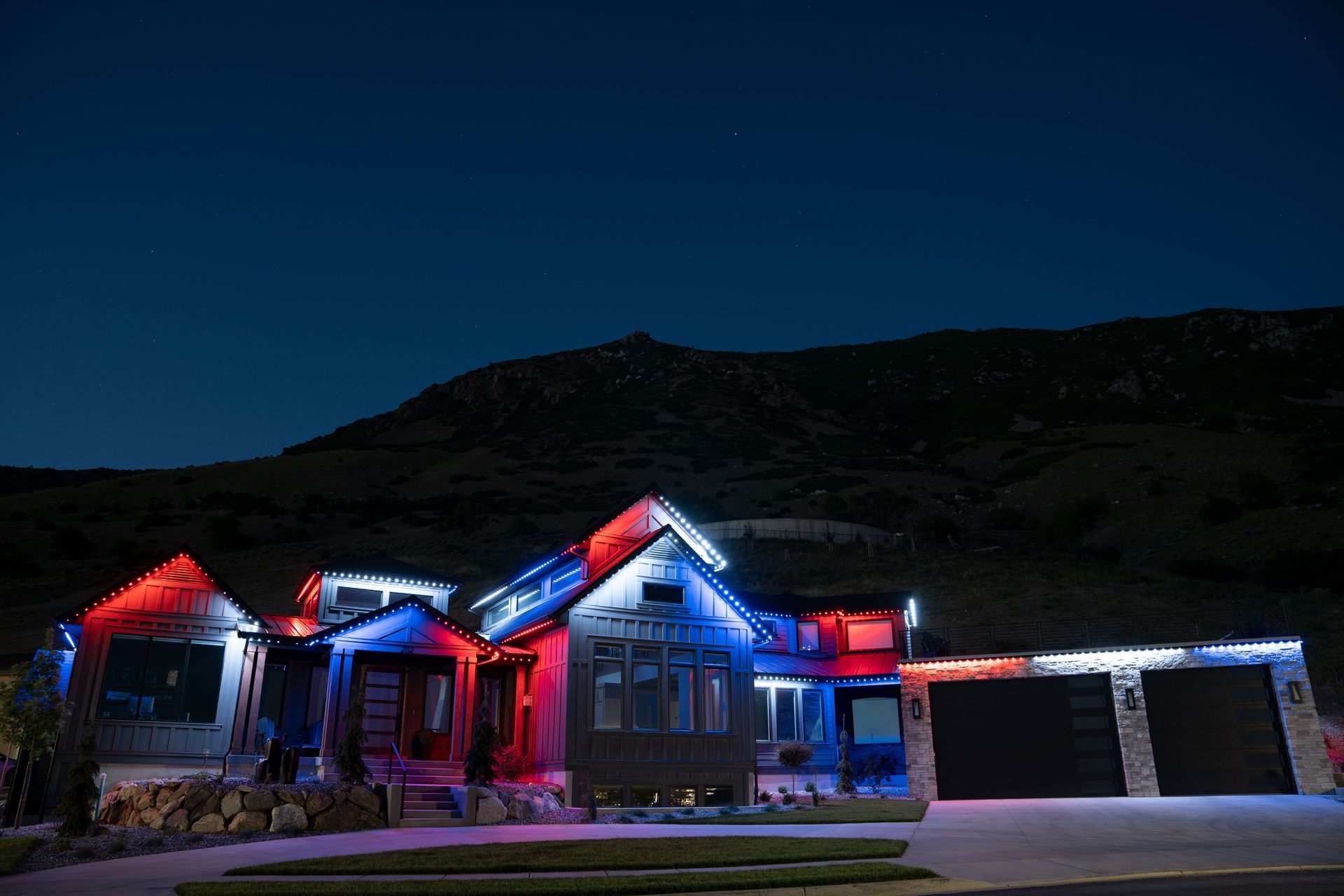 A house is lit up with red, white and blue lights at night.