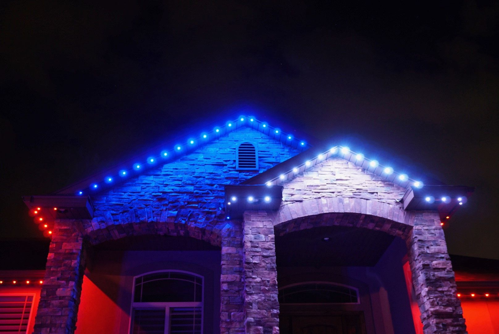 A house is lit up with blue and red lights at night.