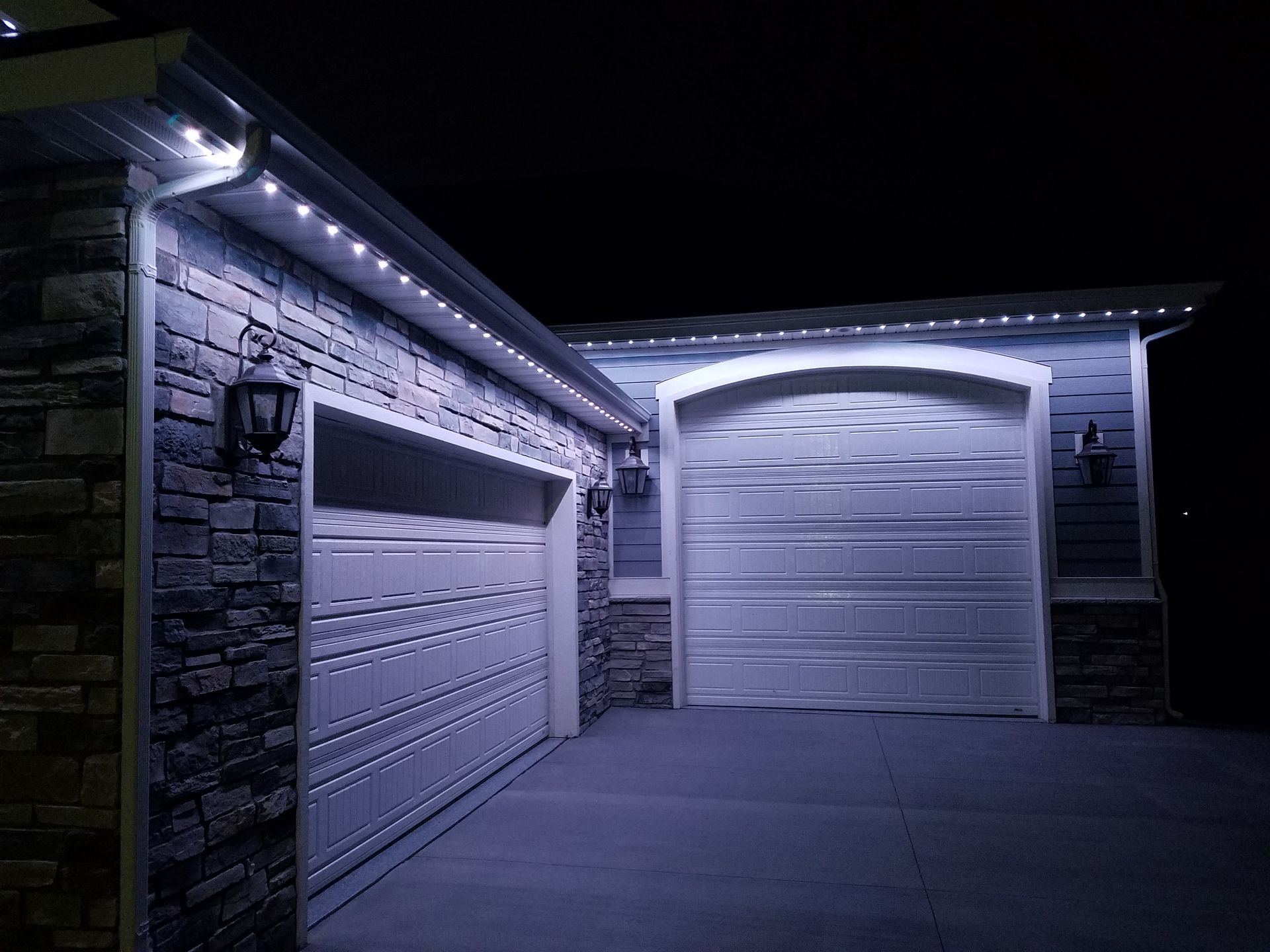 A house with two garage doors is lit up at night.