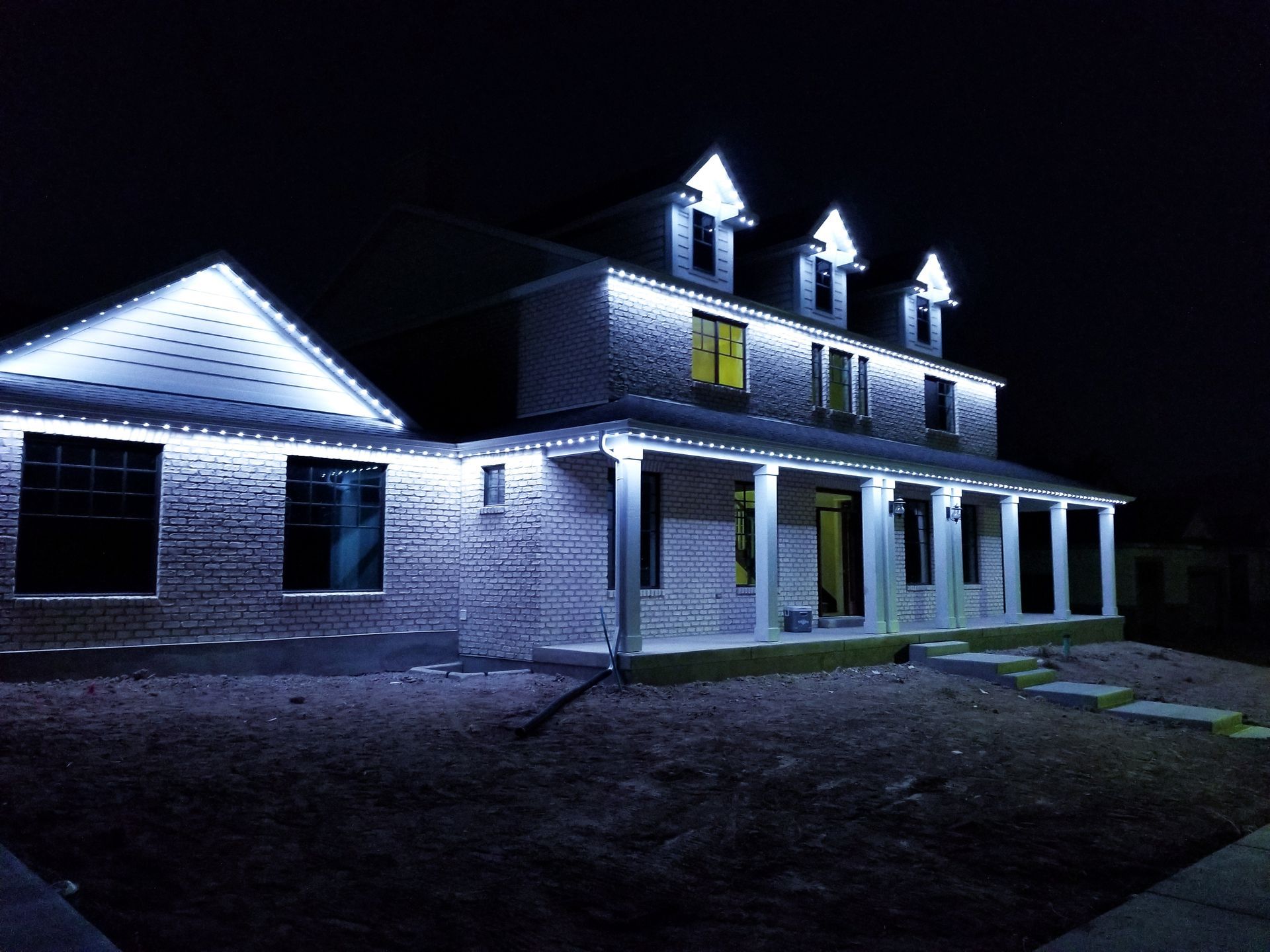 A large house is lit up at night with blue lights.