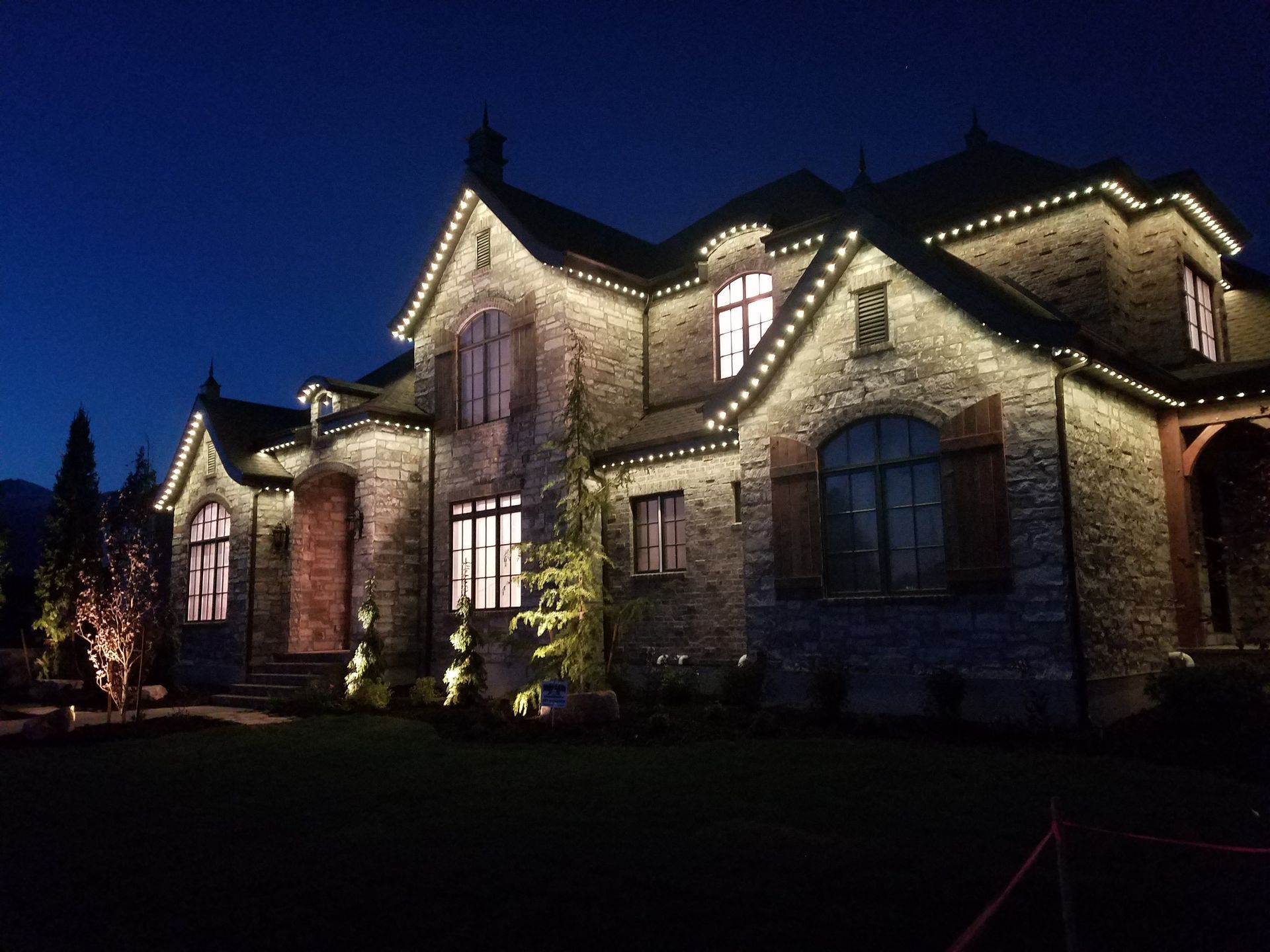 A large brick house is lit up at night with christmas lights.