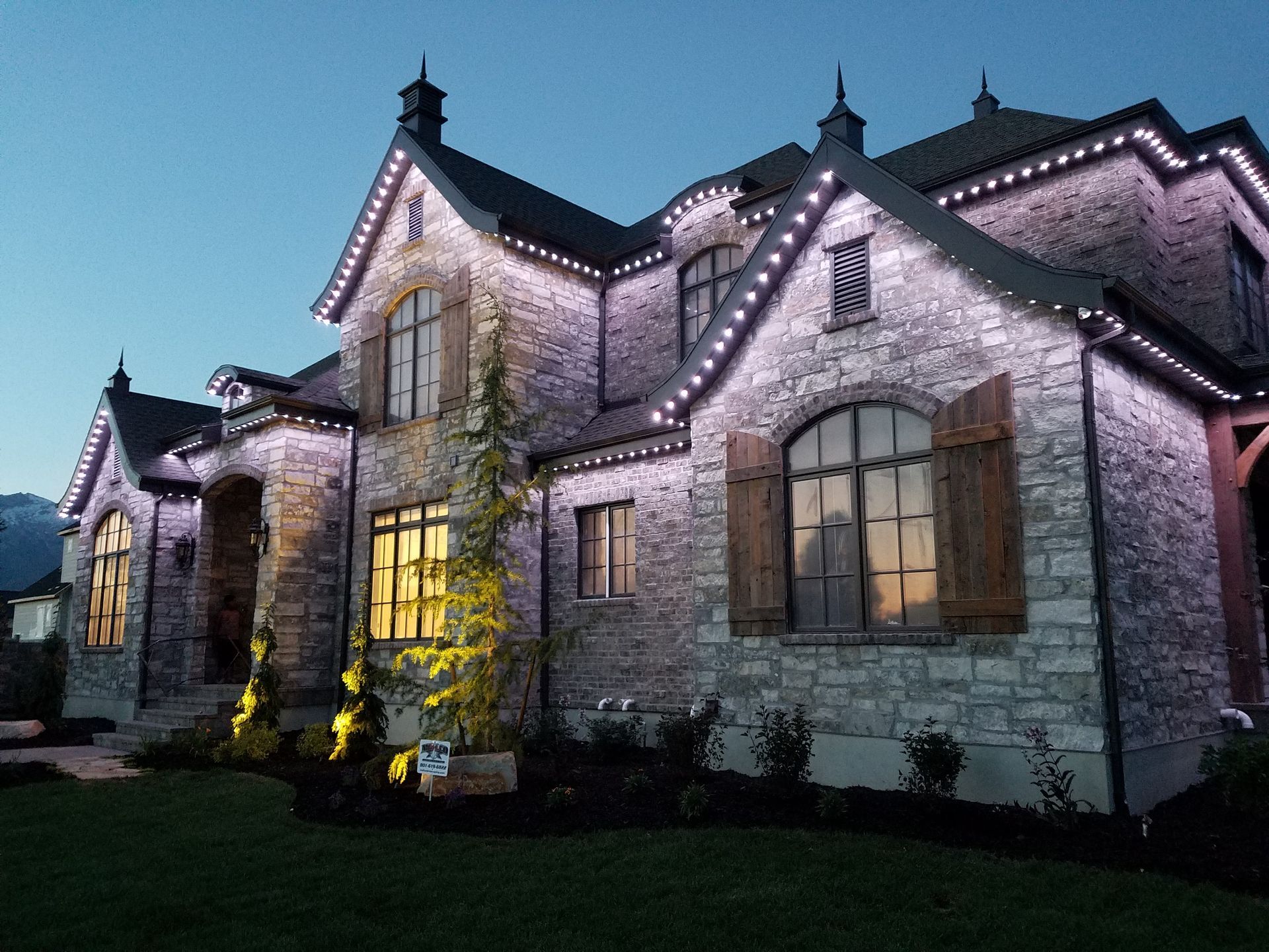 A large brick house is lit up with purple lights at night.