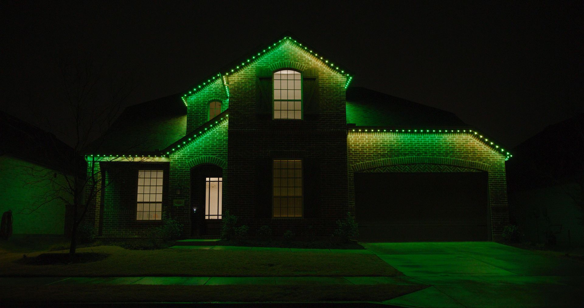 A house is lit up with green christmas lights at night.