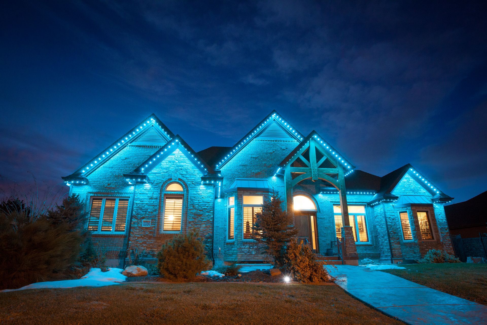 A large house is lit up with blue lights at night.